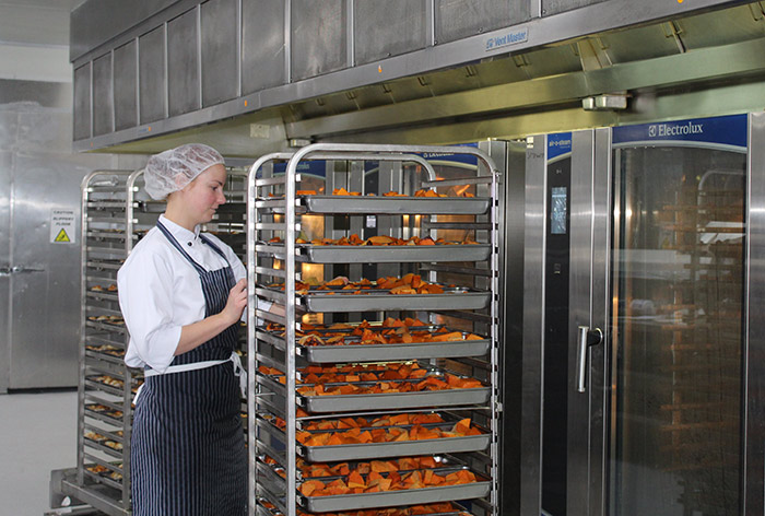 A female pushing a trolley of food in a retirement village kitchen