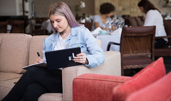 A woman studying on the lounge with a tablet