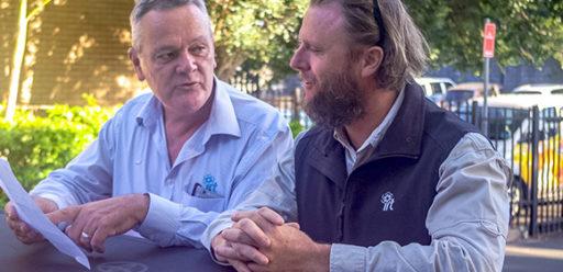 Two facilities management staff discussing the next job on bonnet of work truck