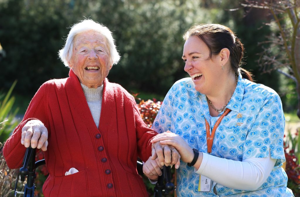 Aged care nurse laughing with elderly woman